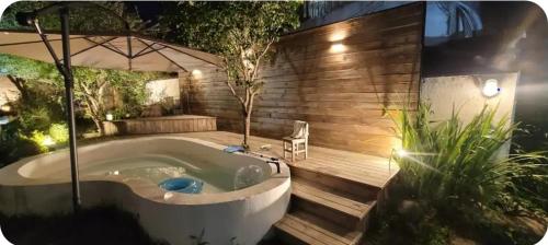 a jacuzzi tub in a garden with an umbrella at 경상북도 감성숙소 청화소담 in Yeongcheon