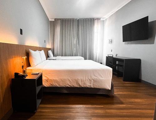 a hotel room with a bed and a television at Hotel Del Rey by Poty - RUA XV DE NOVEMBRO in Curitiba