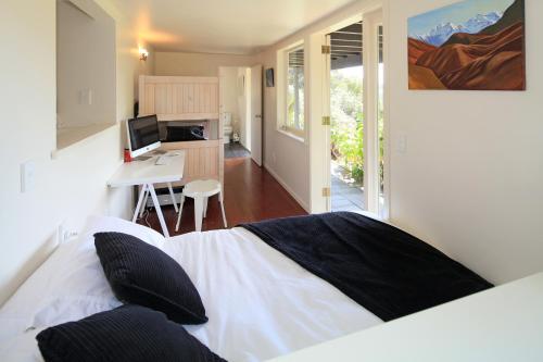 a bedroom with a bed and a desk with a computer at Little Palm Beach Hideaway in Waiheke Island