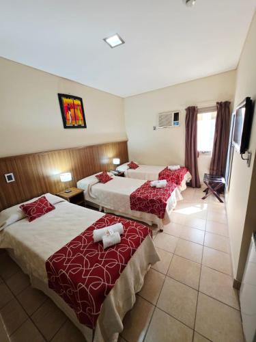 a hotel room with three beds with red sheets at Hotel Confianza in Corrientes