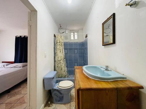 a bathroom with a sink and a toilet and a bed at Windy days Apartments in Utila