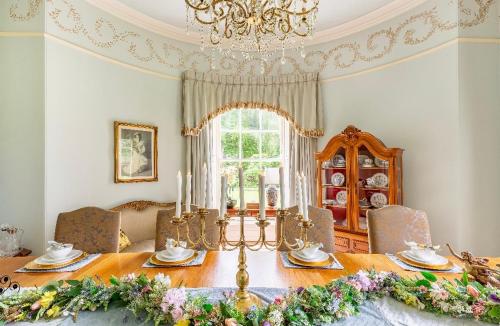 a dining room with a table and a chandelier at Unique Manor House PLUS Jacuzzi PLUS BBQ Cabin in Maybole