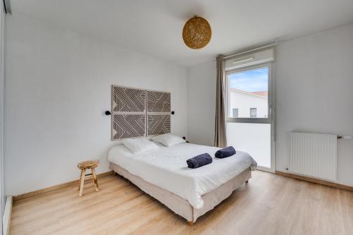 a white bedroom with a bed and a large window at Ô Bon Vivre - Vidéo-projecteur, Wifi, Netflix inclut, Terrasse in Toulouse