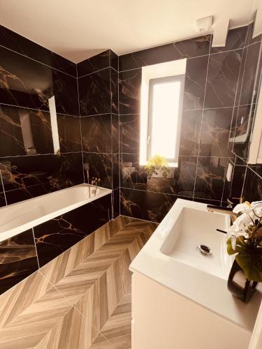 a bathroom with a white sink and a black wall at Le T3 Élégance Lyon aéroport in Janneyrias
