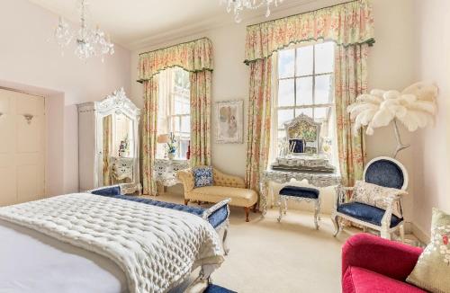 a bedroom with a bed and chairs and a chandelier at Unique Manor House PLUS Jacuzzi PLUS BBQ Cabin in Maybole