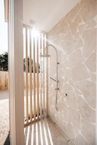 a shower in a bathroom with a stone wall at Bay Days - Binalong Bay in Binalong Bay