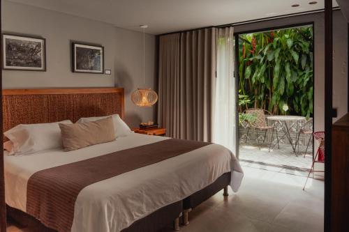a bedroom with a bed and a balcony with a table at Sui Boutique Hotel in Medellín
