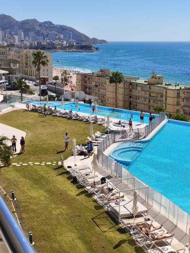 a large swimming pool next to the ocean with people at Sunset Cliffs Luxury Apartment Benidorm in Benidorm
