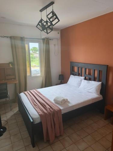 a bedroom with a large bed with white sheets and a window at 'Belkaz in Port-Gentil