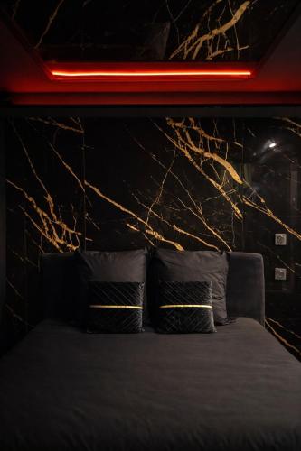 a bedroom with a bed with a black wall and lights at Paradise Room - Spa & Sauna de Luxe à Yutz in Basse-Yutz