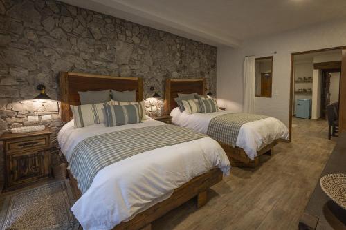a bedroom with two beds and a stone wall at Anae en ValQuirico in Santeagueda