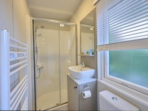 a white bathroom with a sink and a shower at Sunseeker in Goedereede