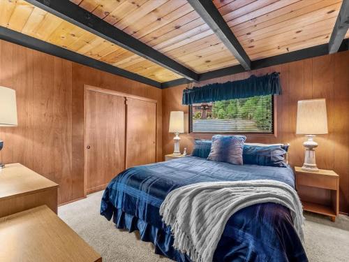 a bedroom with a blue bed and wooden walls at 1st Cabin in Homewood