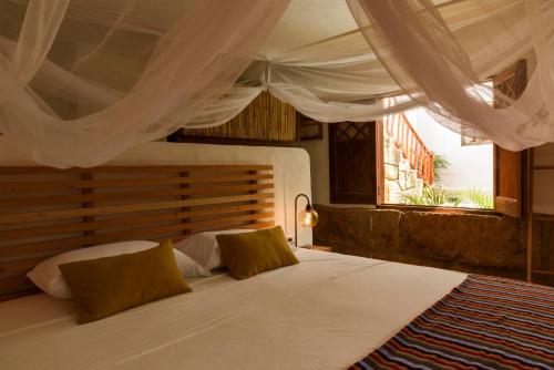 a bedroom with a large white bed with a window at Romantic Colonial Charm Barichara w Jacuzzi in Barichara