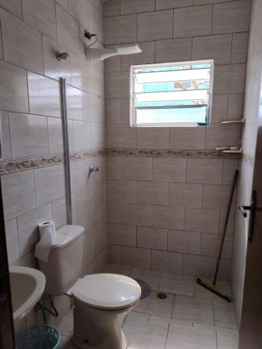 a bathroom with a toilet and a sink and a window at Casa Garcia in Ilha Comprida