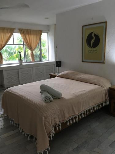 a bedroom with a bed with a blanket and two windows at casa HIKURI in Cancún