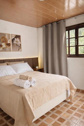 a bedroom with a bed with towels on it at Chalés do Lago Lumiar in Nova Friburgo