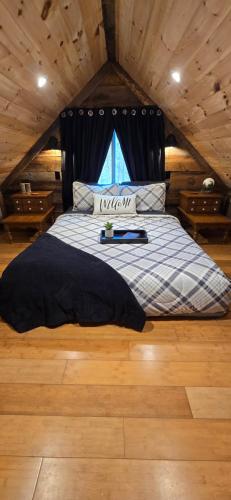 a bed with a black headboard in a room at Couples Getaway Cabin with a Loft Bed - Firepit - Creek Access in Dahlonega