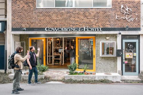 two people walking in front of a building at Kotori Coworking & Hostel Takamatsu in Takamatsu