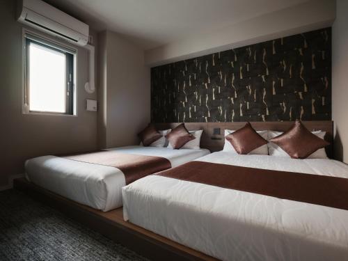 a bedroom with two beds and a window at GRAND MONday ASAKUSA in Tokyo