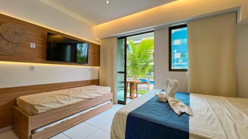 a bedroom with a bed and a flat screen tv at Reserva Muro Alto - Makia Beach Experience in Porto De Galinhas