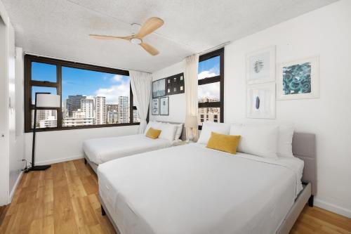 two beds in a white room with a large window at 17FL Fully Renovated, 5 mins to Beach with Parking in Honolulu