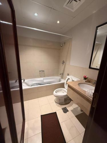 a bathroom with a tub and a toilet and a sink at كيان ايقونة الشاطئ ｋａｙａｎ in King Abdullah Economic City