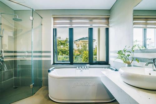 a bathroom with a tub and a sink and a window at Villa FLC Sầm Sơn Thanh Hoá in Sầm Sơn