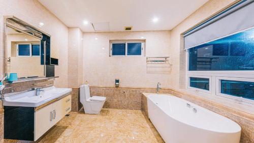 a bathroom with a tub and a toilet and a sink at Happy Villa in Sầm Sơn