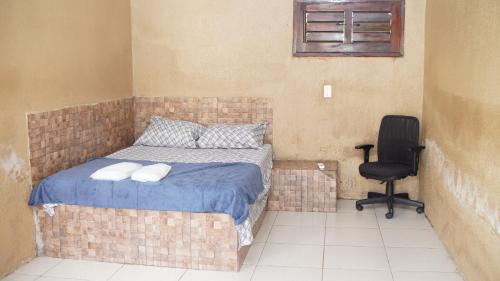 a bedroom with a bed and a black chair at Sítio Resenha in Caucaia