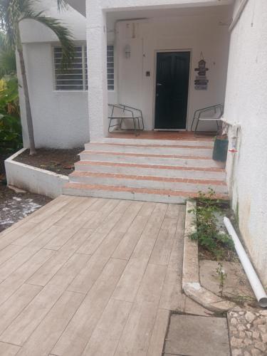 a porch with stairs leading to a house with a door at Cocoon apartment with garden, quiet in Simpson Bay