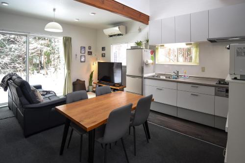 a kitchen and dining room with a table and a couch at Sai's House Hakuba in Hakuba