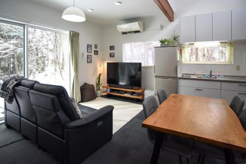 a kitchen and a living room with a table and a television at Sai's House Hakuba in Hakuba