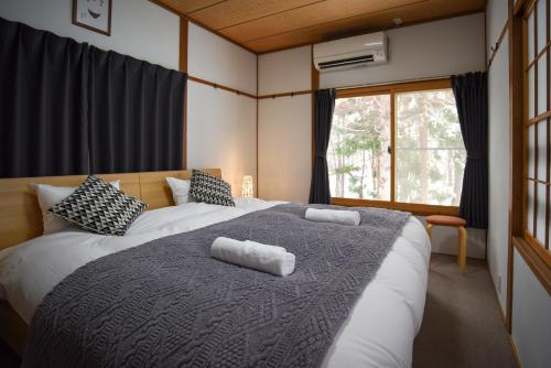 a bedroom with a large bed with two pillows on it at Sai's House Hakuba in Hakuba