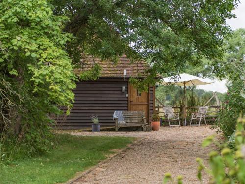 a cabin with a bench and an umbrella at Heron Barn in Hollingbourne