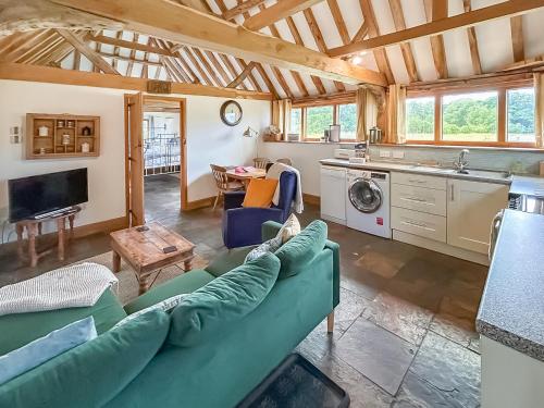 a living room with a couch and a kitchen at Heron Barn in Hollingbourne