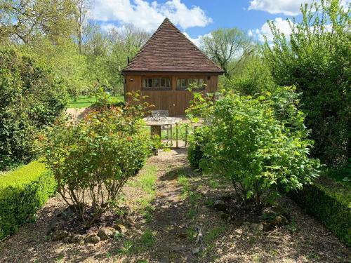 a garden with a table and a cabin in the background at Heron Barn in Hollingbourne