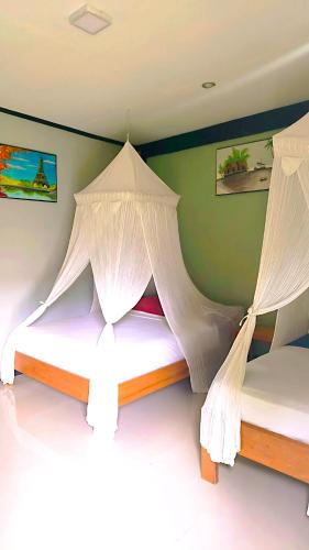 two beds in a room with white mosquito nets at Nirvana bungalow's in Boras