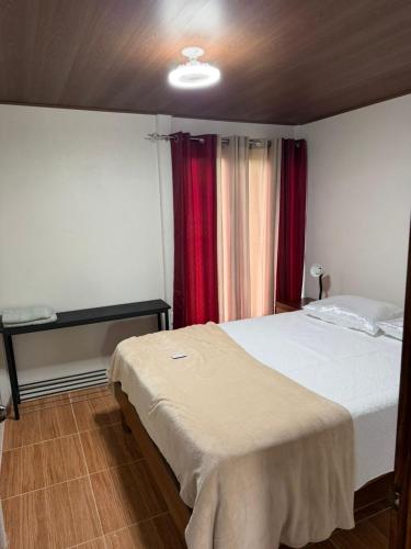 a bedroom with a large bed and red curtains at Ticary Nature Homes in Guápiles