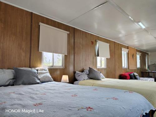 two beds in a room with wooden walls and windows at Quinta Aroma Zempoala in Zempoala