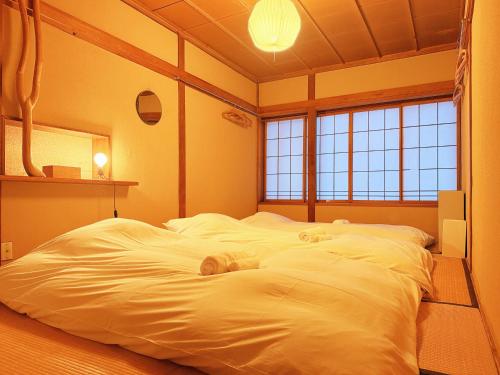 a large white bed in a room with windows at Hakuba Hospitality Inn YUKINOSO in Hakuba