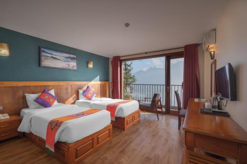 a hotel room with two beds and a television at Sapa Vista Hotel in Sapa