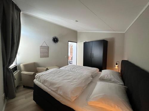 a bedroom with a large white bed and a chair at Aquaronde 108 in Lemmer