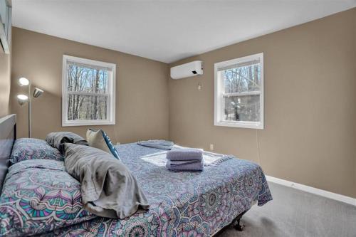 a bedroom with a bed and two windows at Arrowhead Lakefront Chalet Private Lake Access in Pocono Lake