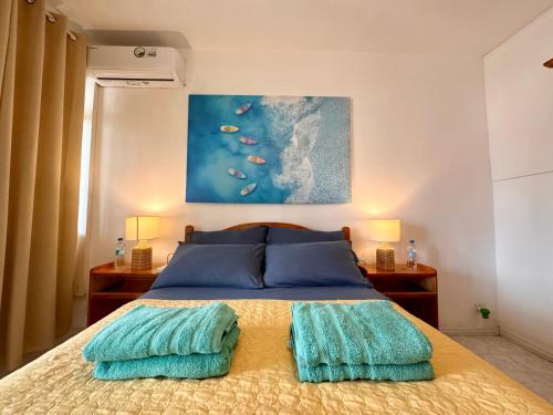 a bedroom with a bed with blue pillows and a painting at Fibonacci Beachfront Apartment in Flic-en-Flac