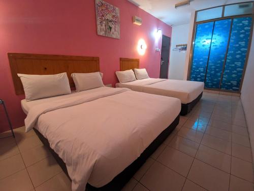 two beds in a room with red walls at Midah Inn Puchong in Puchong