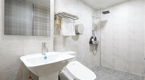 a white bathroom with a sink and a toilet at sotam stay hotel in Taeam
