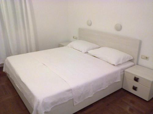 a white bed with two pillows and a night stand at Apartment in Okrug Gornji 6167 in Trogir