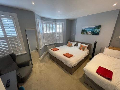 a bedroom with two beds and a couch and windows at Home in Greenwich near the O2 in London
