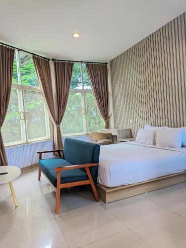 a bedroom with a large bed and a blue chair at K Residence Surabaya in Surabaya